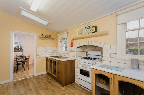 a kitchen with a stove top oven next to a table at Albany Historic Cottage by the BnB Collection in Albany