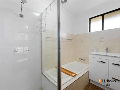 Un baño blanco con ducha y lavabo. en Casa al Mare, en Iluka