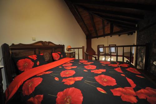 a bedroom with a bed with red flowers on it at Arolithos-Kaimaktsalan in Palaios Agios Athanasios