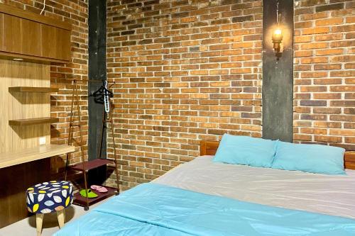 Schlafzimmer mit Ziegelwand und Bett in der Unterkunft Pondok Pakde Villa by TwoSpaces, Jogja in Soprayan