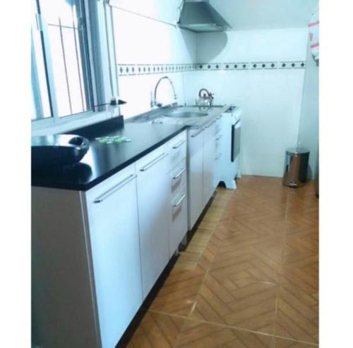 uma cozinha com armários brancos e um balcão preto em Lo de Sandra em Costa Azul