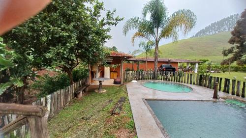 a house with a swimming pool in front of a fence at Sitio Reis Membeca in Paraíba do Sul