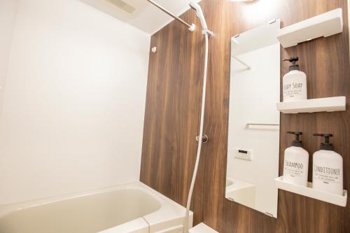 a bathroom with a tub and a shower with two soap bottles at The most comfortable and best choice for accommodation in Yoyogi SioY5 in Tokyo
