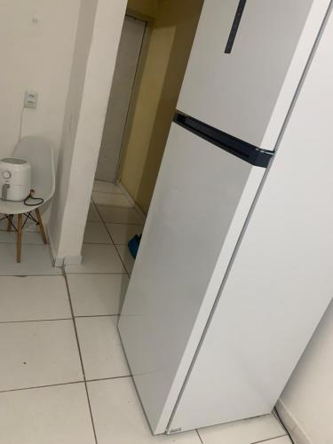 um frigorífico branco num quarto com uma mesa em Apartamento próximo ao aeroporto e praia em Recife