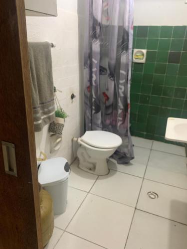 uma casa de banho com um WC e uma cortina de chuveiro verde em Apartamento próximo ao aeroporto e praia em Recife