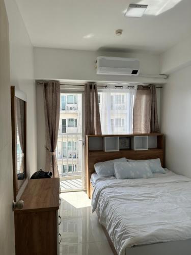 a bedroom with a bed and a large window at Bright & Breezy 2 BR Unit with Balcony in Manila