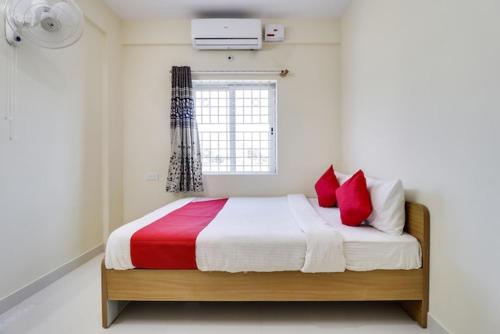 een slaapkamer met een bed met rode kussens en een raam bij Anjana residency in Bangalore