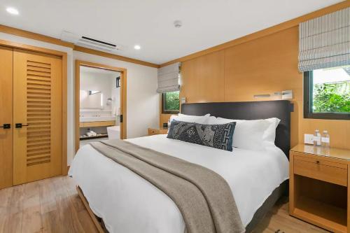 a bedroom with a large white bed and a bathroom at SA Carbon Beach Suites in Malibu