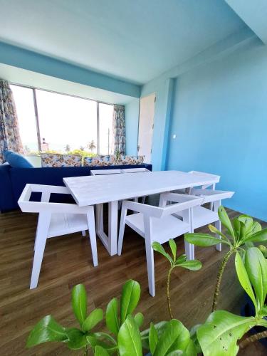 a white table and benches in a room with plants at X Mirissa in Mirissa