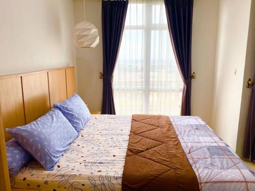 a bedroom with a bed with blue pillows and a window at Apt Vasanta Innopark Studio S1oN with Pool in Jarakasta