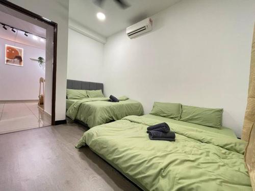 10 Pax-Cozy Family Suite Landmark 2 في كاجانغ: سريرين في غرفة مع شراشف خضراء
