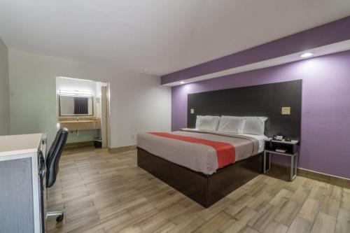 1 dormitorio con 1 cama grande y pared morada en Holiday Terrace Motel en Houston