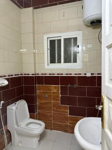 a bathroom with a toilet and a sink and a window at فندق البديل in Al Madinah
