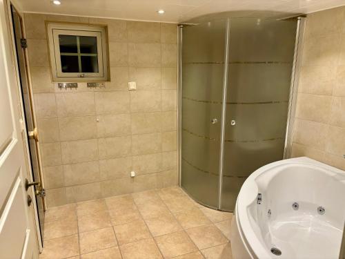 a bathroom with a shower and a tub and a toilet at The Gardeners House, Lake View & Sauna in Vreta Kloster
