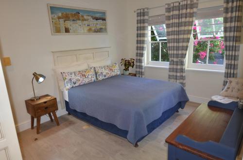- une chambre avec un lit bleu et 2 fenêtres dans l'établissement Mont Vue Manor, à Franschhoek
