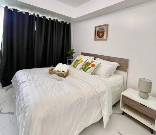 a white bedroom with a large white bed with black curtains at Azure Urban Resort - CITY VIEW 1BR - PS4, Billiards, Netflix, Karaoke in Manila