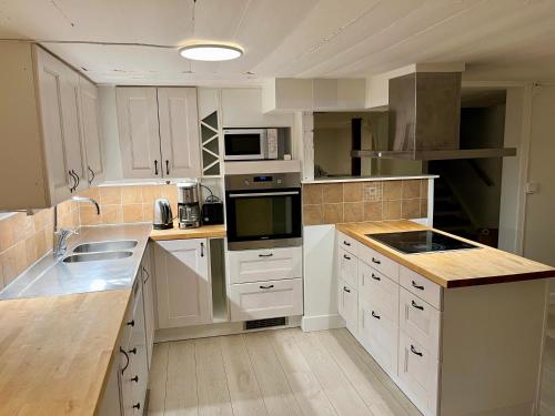 a kitchen with white cabinets and white appliances at The Gardeners House, Lake View & Sauna in Vreta Kloster