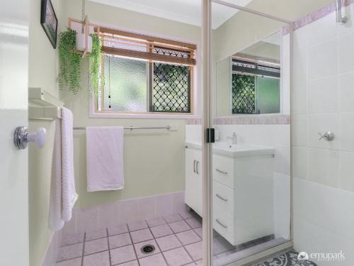 La salle de bains blanche est pourvue d'une douche et d'un lavabo. dans l'établissement The Breezy Emu, à Emu Park