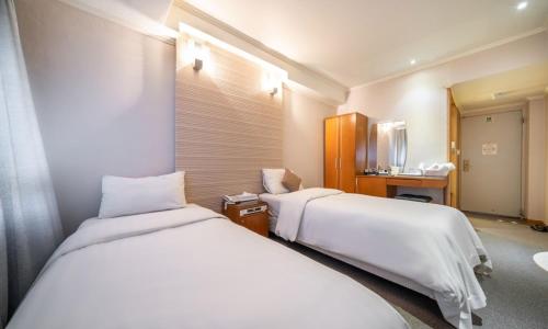 a hotel room with two beds and a desk at Ansan Seowon Tourist Hotel in Ansan