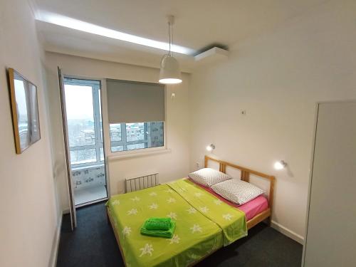 um pequeno quarto com uma cama e uma janela em Светлая квартира в сердце города em Almaty
