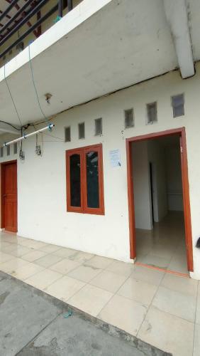 een wit gebouw met een rode deur en ramen bij Almalik Kost in Serang