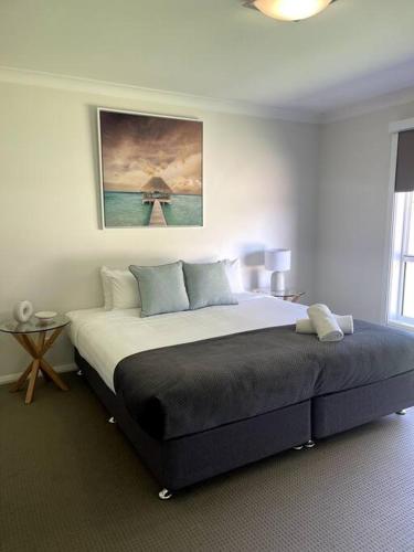 a bedroom with a large bed with a painting on the wall at Stylish Open Plan Retreat in Wagga Wagga