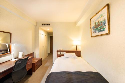 宇都宮市にあるホテルニューイタヤのベッドとデスクが備わるホテルルームです。