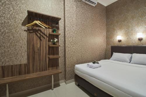 Schlafzimmer mit einem weißen Bett und einem Holzschrank in der Unterkunft FLAMENCO URBAN STAY in Jakarta
