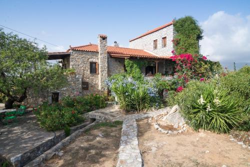 a stone house with flowers in front of it at Elise Cottage in Vathi
