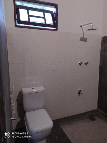 a bathroom with a white toilet and a window at Priyanka Villa in Bentota