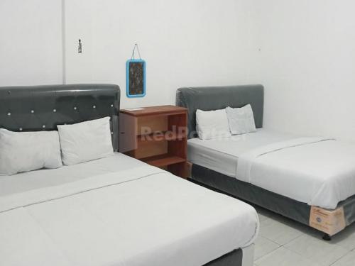 two beds sitting next to each other in a room at RedDoorz @ Pantai Sayangheulang in Cilauteureun