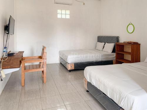 a room with two beds and a desk and a chair at RedDoorz @ Pantai Sayangheulang in Cilauteureun