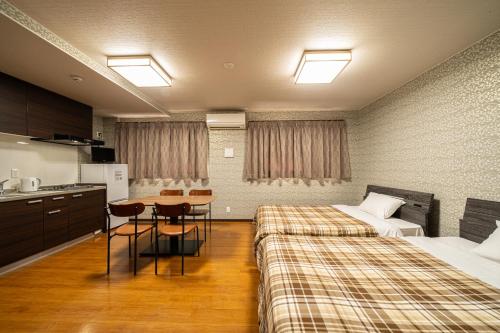 別府市にあるBEPPU HOSTEL U&Tのベッド2台とテーブルが備わるホテルルームです。