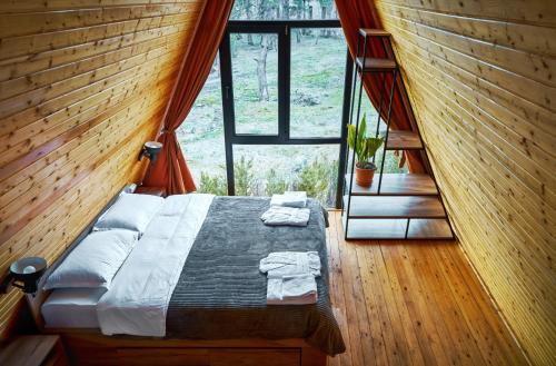 Bett in einem Zimmer mit einem großen Fenster in der Unterkunft Ja ge • ჟა ღე in Tsalka