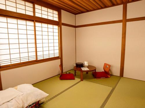 a room with a bed and a table and a window at Guest House Nakamura in Ama