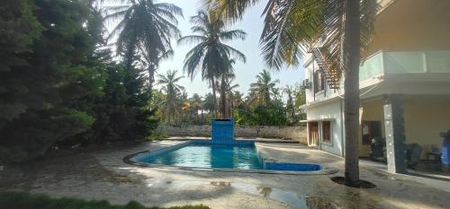a swimming pool in front of a house with palm trees at SHAN Stay home Mysore No in Mysore