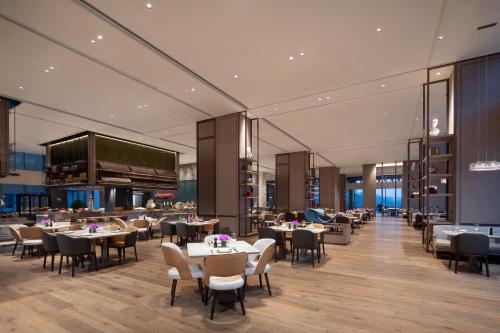 Un restaurante con mesas y sillas y una pantalla grande. en 宁波东钱湖望岚酒店, en Ningbo