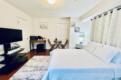 a bedroom with a white bed and a flat screen tv at Studio in the heart of Rockville in Rockville