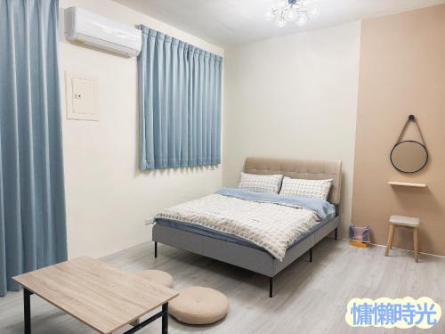 Dormitorio pequeño con cama y mesa en Lazy Time B&B, en Miaoli