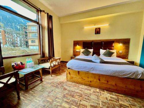 een slaapkamer met een groot bed en een groot raam bij Kalinga's - Majestic Mountain View in Manāli