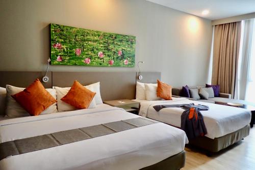 a hotel room with two beds and a couch at Qliq Damansara Hotel in Petaling Jaya