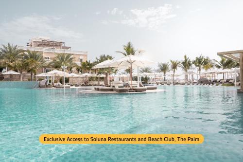 - une piscine avec des chaises et des parasols dans un complexe dans l'établissement Wyndham Dubai Marina, à Dubaï