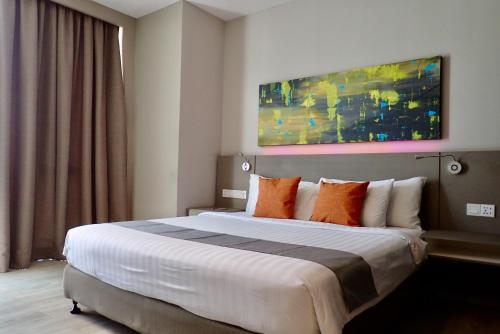 a hotel room with a large bed with orange pillows at Qliq Damansara Hotel in Petaling Jaya