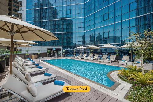 einem Pool mit Stühlen und Sonnenschirmen vor einem Gebäude in der Unterkunft TRYP by Wyndham Dubai in Dubai