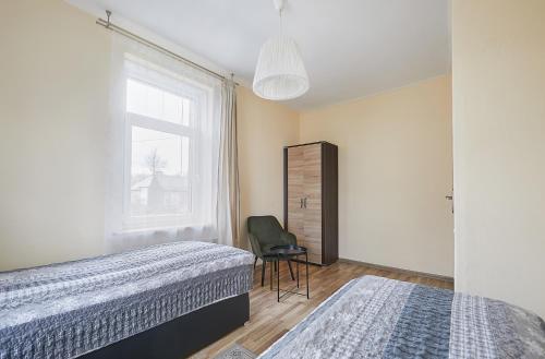 1 dormitorio con 2 camas, silla y ventana en Kauko Laiptu Apartamentai, en Kaunas