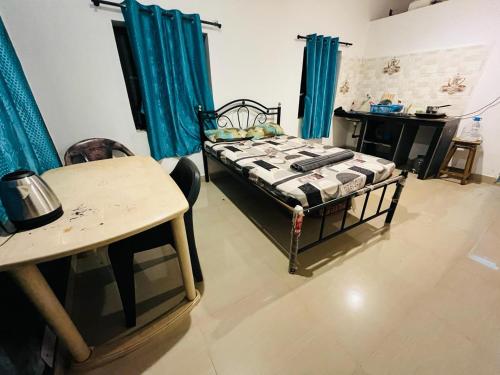 una camera con letto, tavolo e tende blu di Coral Reef - NestinGoa Homestays ad Arambol