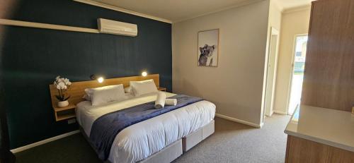 a bedroom with a bed with a blue wall at Billabong Motel in Gunnedah