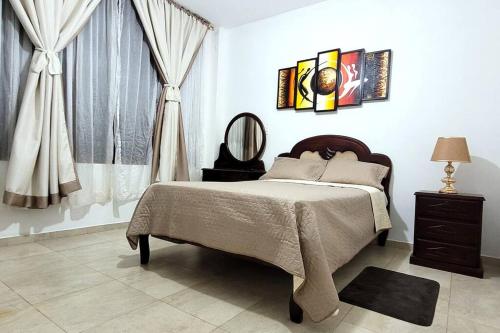 a bedroom with a bed and a mirror and curtains at La Perla House in Sucúa