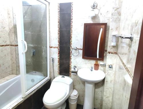 uma casa de banho com um WC, um lavatório e um chuveiro em La Perla House em Sucúa