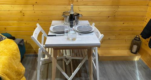 - une table blanche avec des assiettes et des verres dans l'établissement Tiny House - Home-One, à Dannemarie-sur-Crête